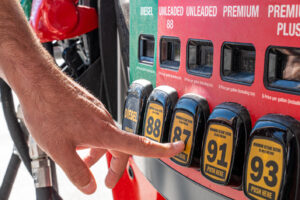 Driver choosing fuel at a gas pump as part of reducing fuel costs and improving gas mileage